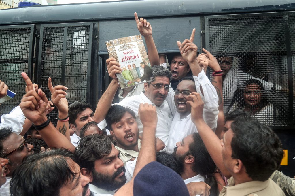 Police personnel detain protesters as they demonstrate in front of Lok Bhawan