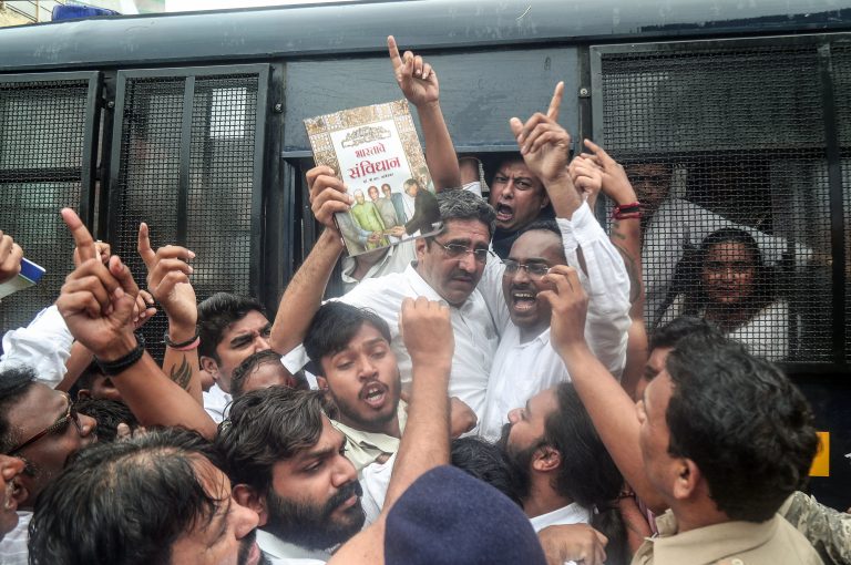 Police personnel detain protesters as they demonstrate in front of Lok Bhawan