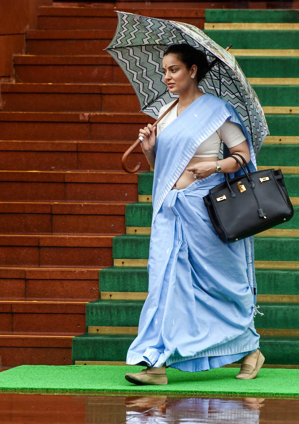 Bharatiya Janata Party MP Kangana Ranaut holds an umbrella amid rain at the Parliament premises during the Monsoon Session